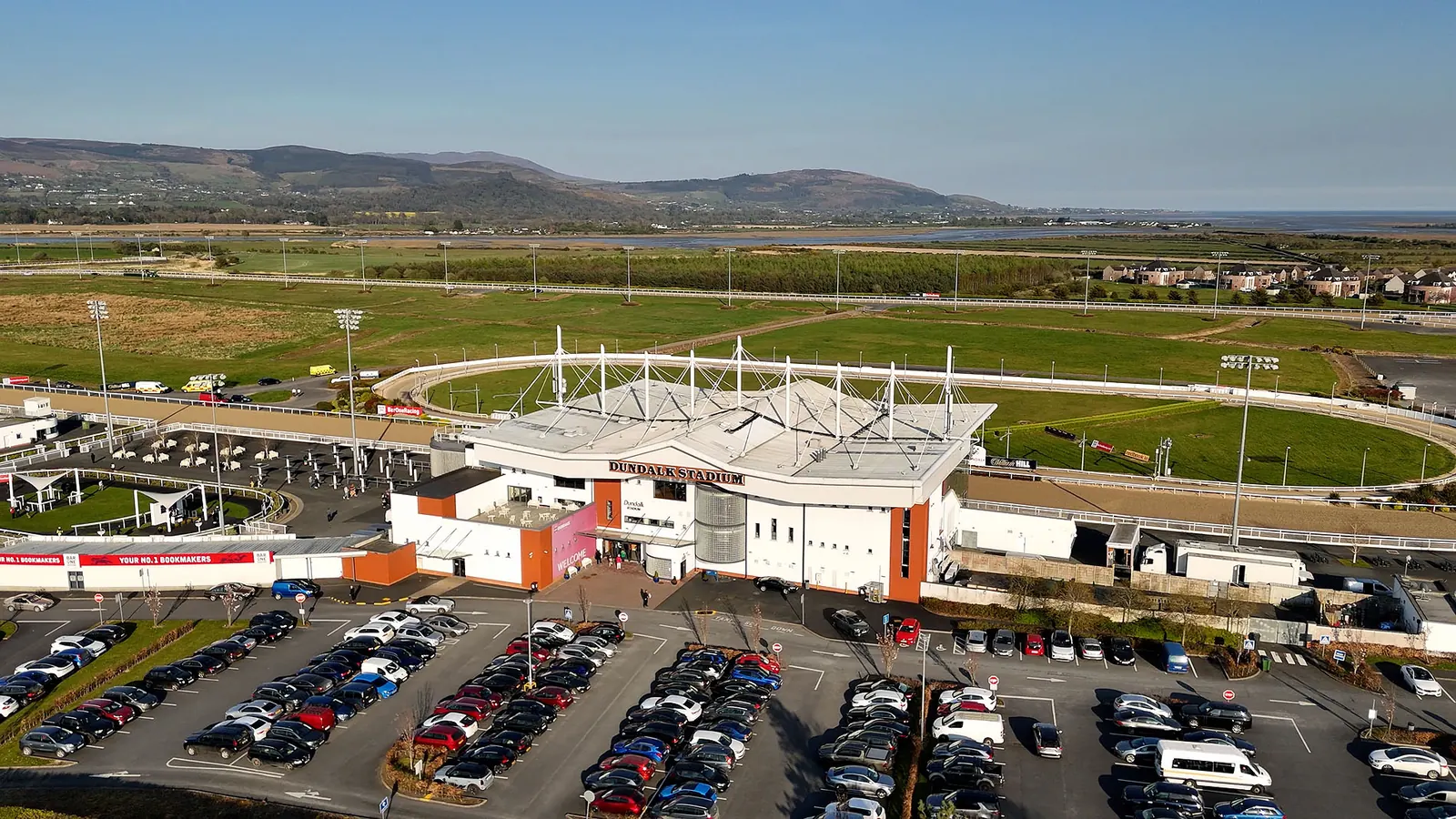 Dundalk Stadium from the air: the grandstand, the inner greyhound track and outer racecourse, the Cooley Mountains behind.
